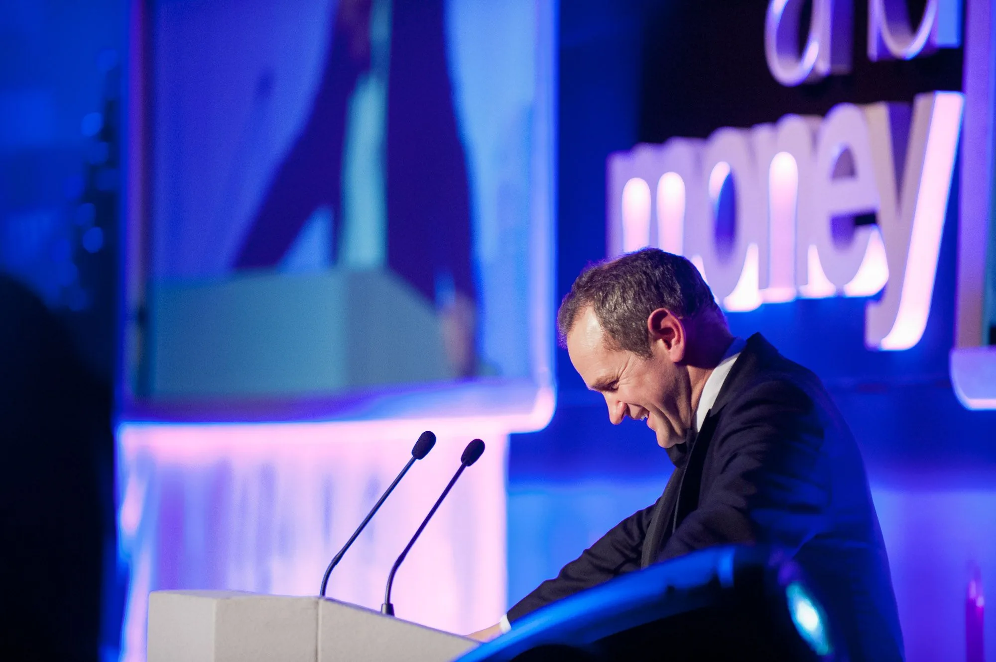 Speaker addressing an audience from a podium at a corporate awards event, event photography by Hector's Eye