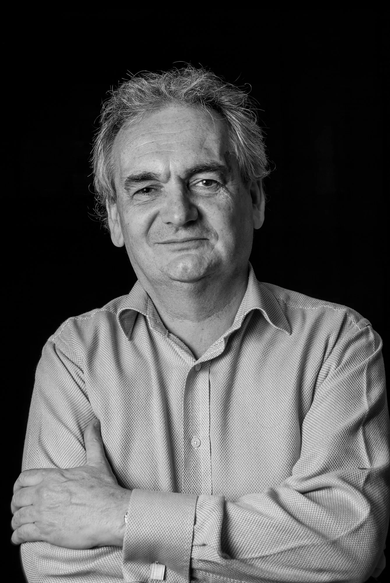 Black and white studio portrait of an older man with arms folded, editorial portrait photography by Hector's Eye