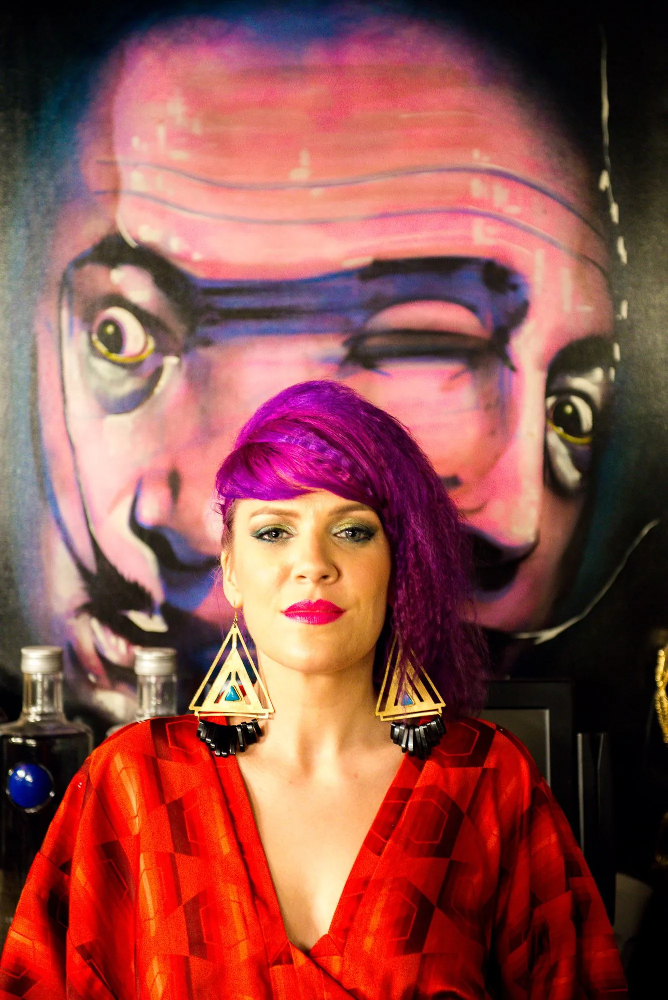 Editorial portrait of a model with pink hair in a red outfit against a painted mural, styled portrait photography by Hector's Eye