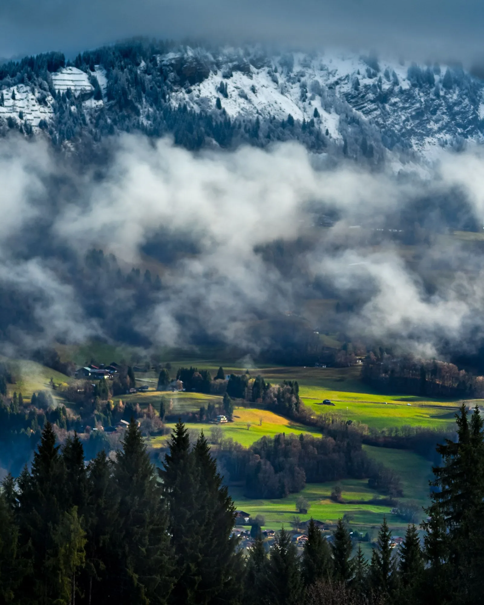 Mist rolling through a green valley beneath snow-capped mountains, landscape photography by Hector's Eye