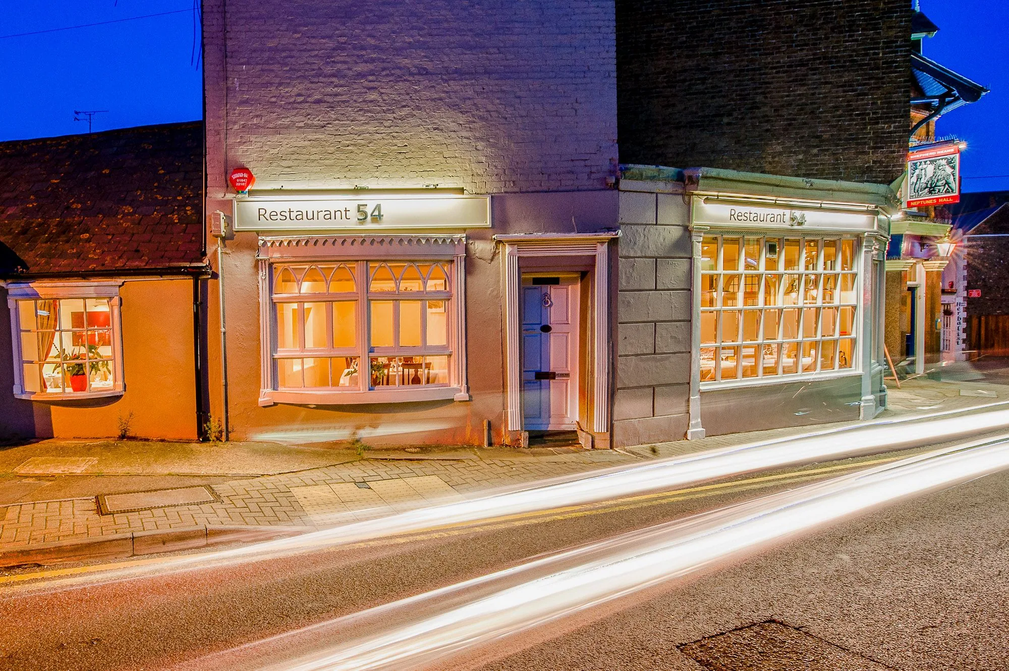 Restaurant exterior at night with light trails from passing traffic, brand storytelling photography by Hector's Eye