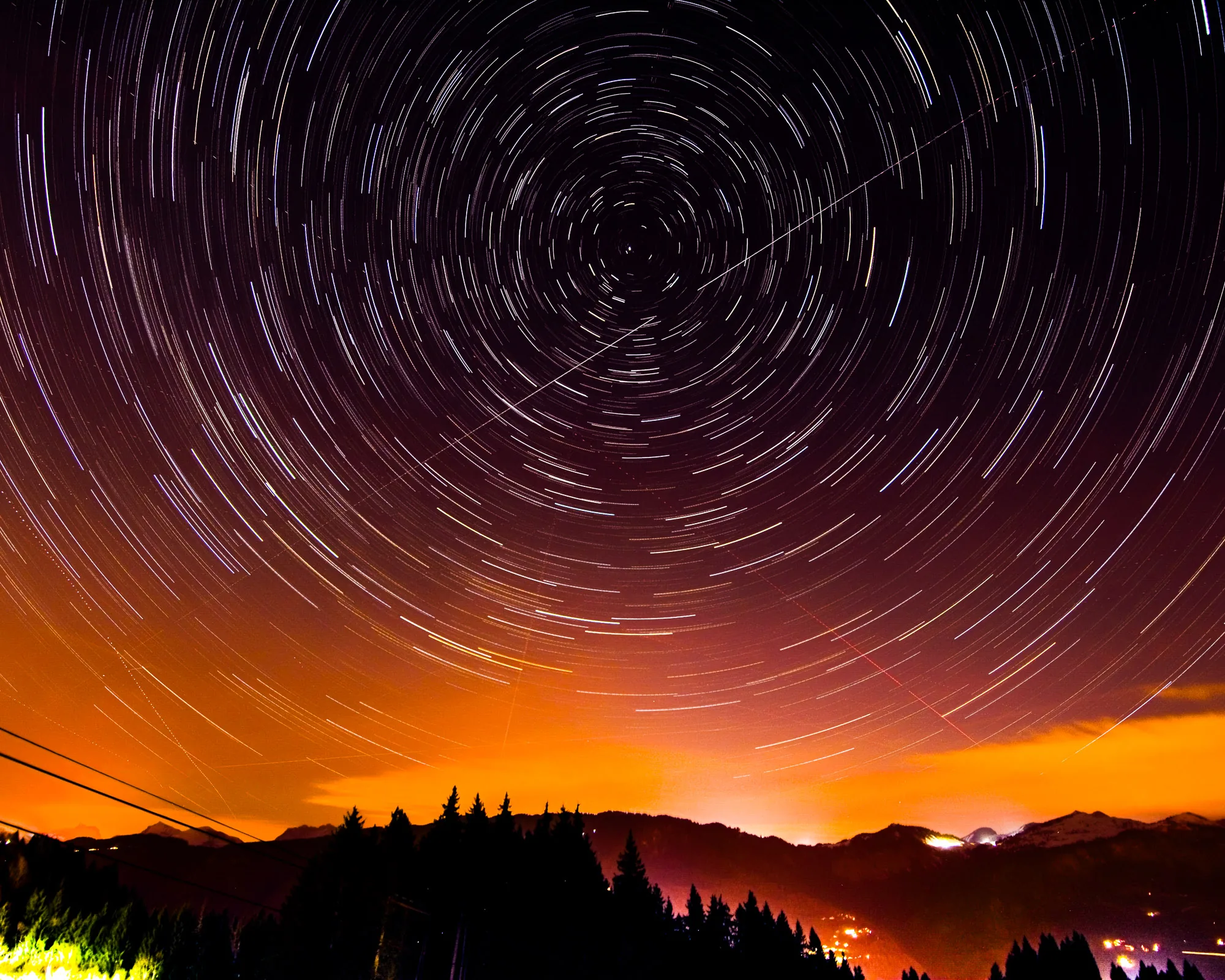 Star trails circling above a mountain valley at night